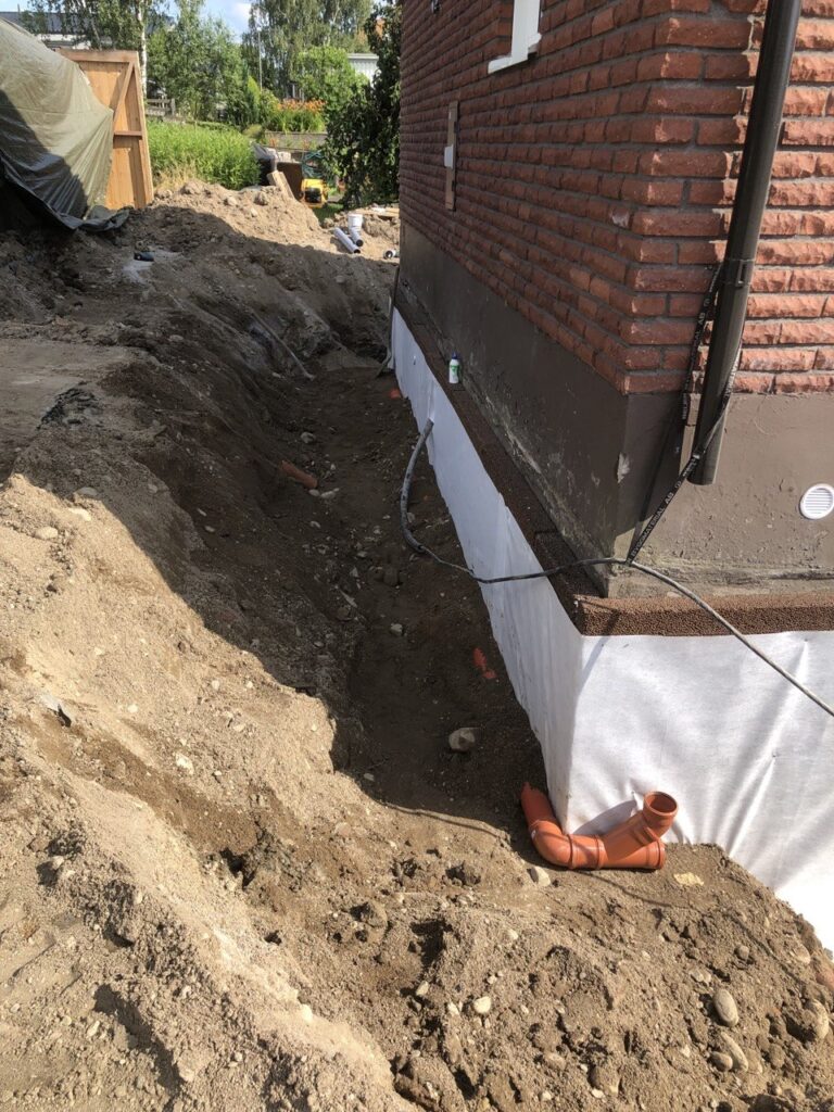 Dräneringsskiva och dagvattenledning installerade vid husgrund under dräneringsarbete i Stenungsund.