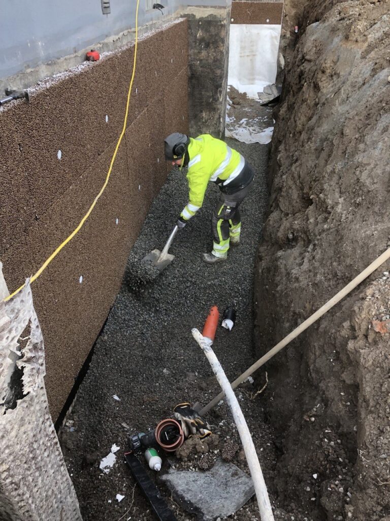 Installation av dräneringsrör och makadam vid husgrund i Trollhättan.
