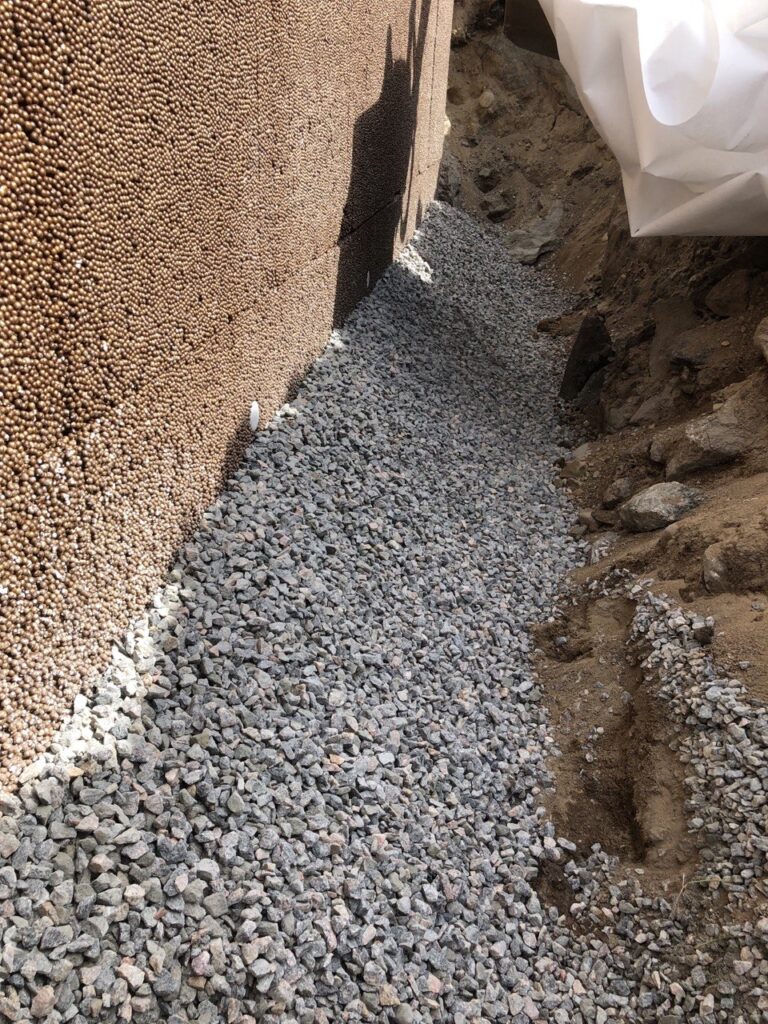 Makadam och dräneringsmaterial vid husgrund under dräneringsarbete i Uddevalla.