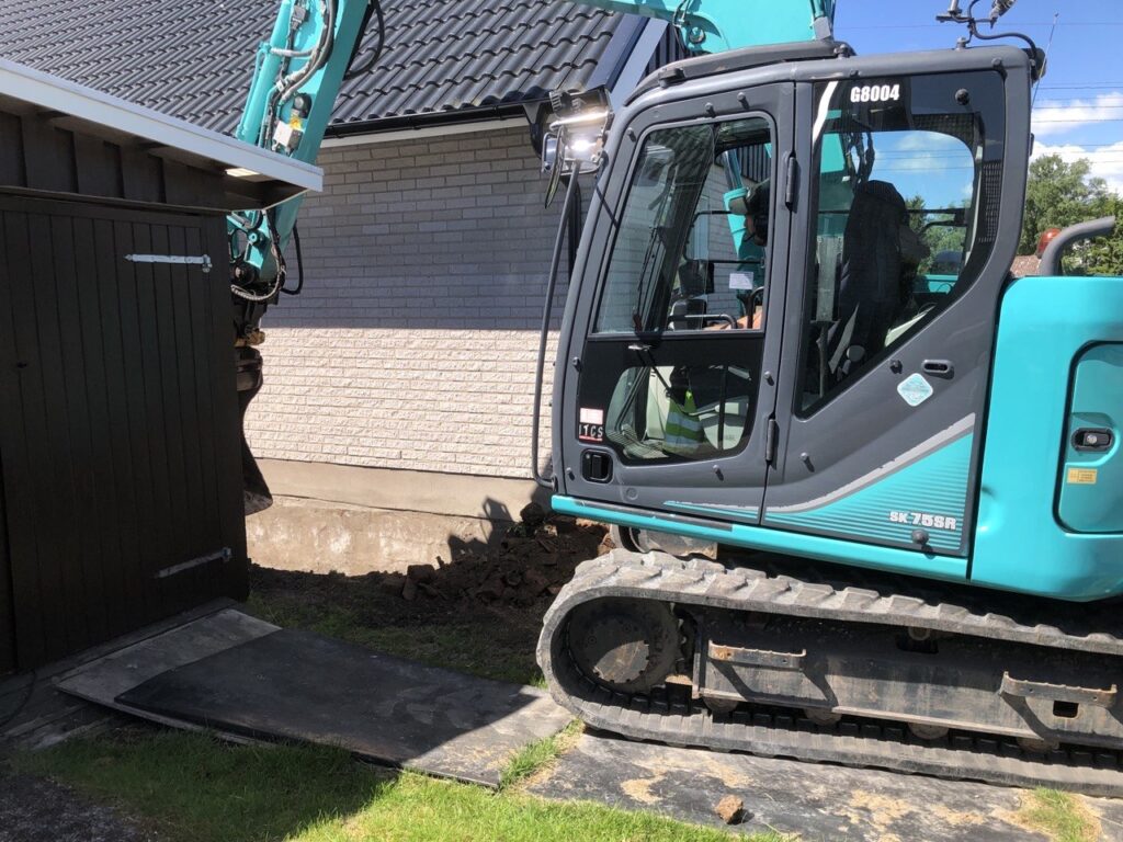Dräneringsarbete i Vänersborg med grävmaskin intill villa.
