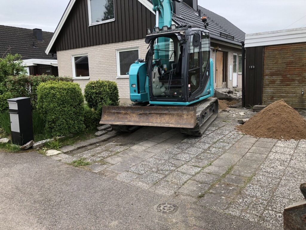 Grävmaskin vid villa under dräneringsarbete i Vänersborg.