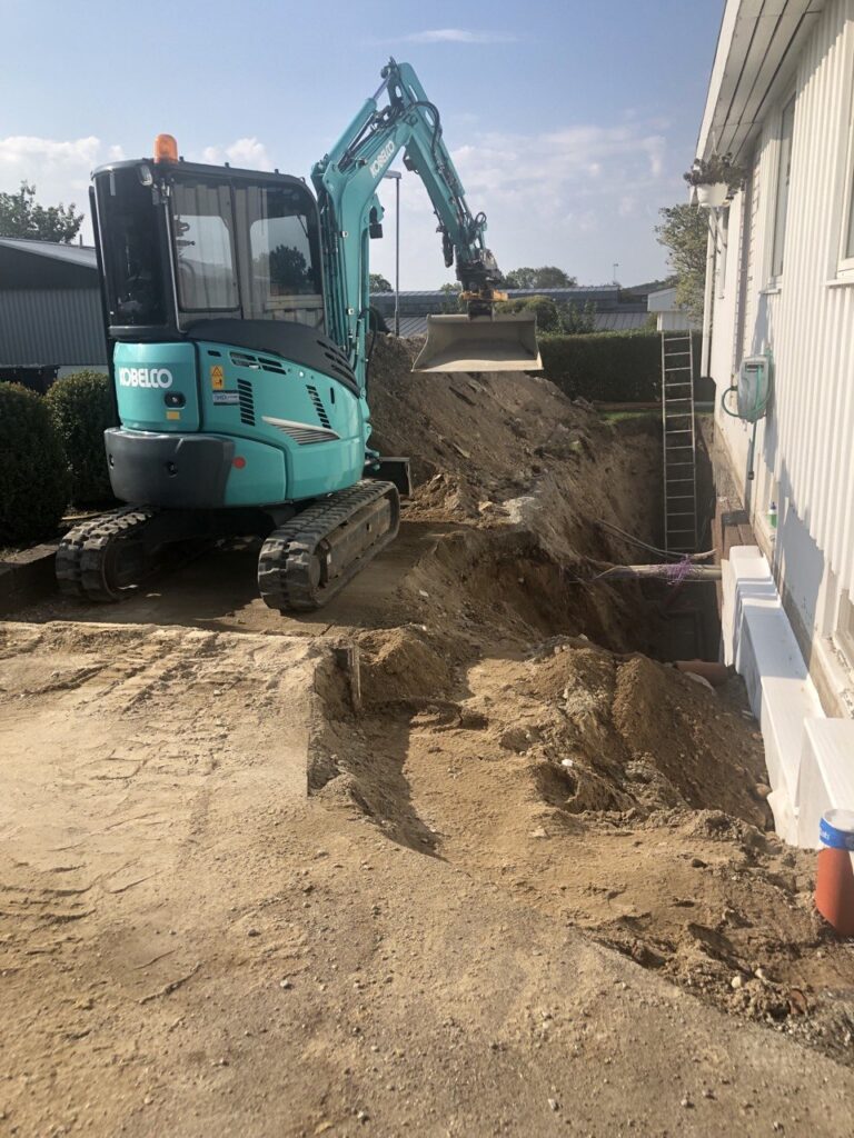 Dräneringsarbete runt husgrund med grävmaskin under pågående projekt i Stenungsund.