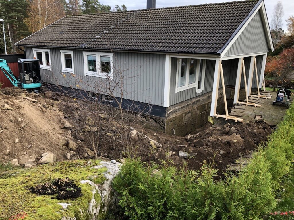 Dräneringsarbete runt villa i Trollhättan med schaktningsarbete längs husgrunden.